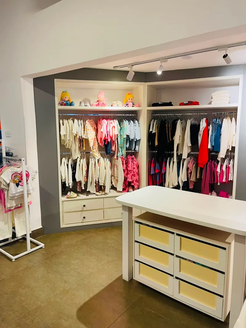 Interior da Leopam Kids com roupas infantis organizadas por cor